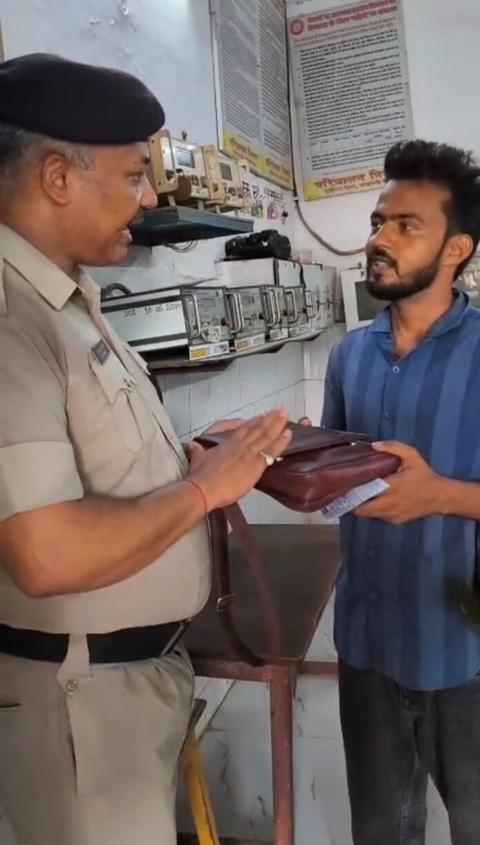 आरपीएफ अधिकारी यात्री को रुपयों से भरा बैग सुपुर्द करते हैं