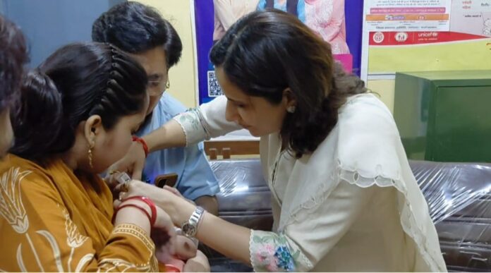 जिलाधिकारी बच्चों को पोलियो टीका दे रही है