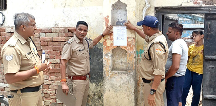 पुलिस नोटिस चस्पा करते हुए