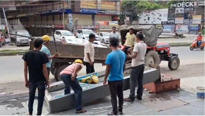 नगर निगम कर्मचारी होर्डिंग्स को तोड़ते हुए