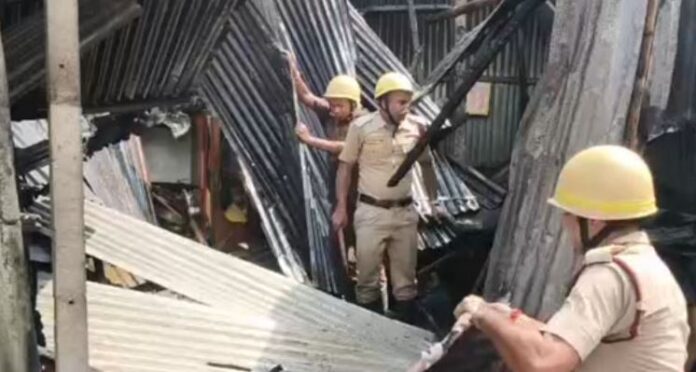 दमकलकर्मी आग को काबू करने के बाद घर के टूटे सामानों को हटाते हुए