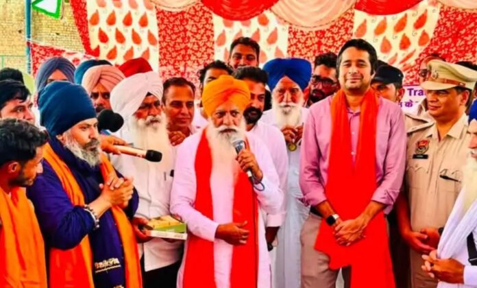 गुरनाम सिंह चढूनी सिरोपा पहनाकर सम्मानित करते।