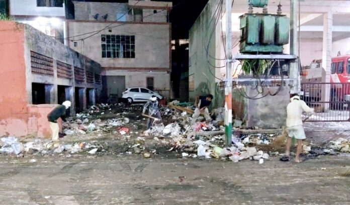 रात को सफाई अभियान चलाए हुए अधिकारी।