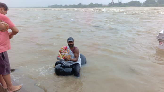 रुद्रेश्वर घाट किनारे महानदी में मूर्ति विसर्जित करते हुए गोताखोर।