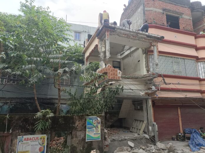 अवैध तीन मंजिला मकान को तोड़ते निगम कर्मचारी