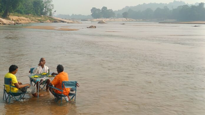 जलाशय किनारे बैठे हुए ग्रामीण।