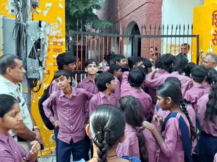 स्कूल के गेट को ताला जड़कर खड़े छात्र।
